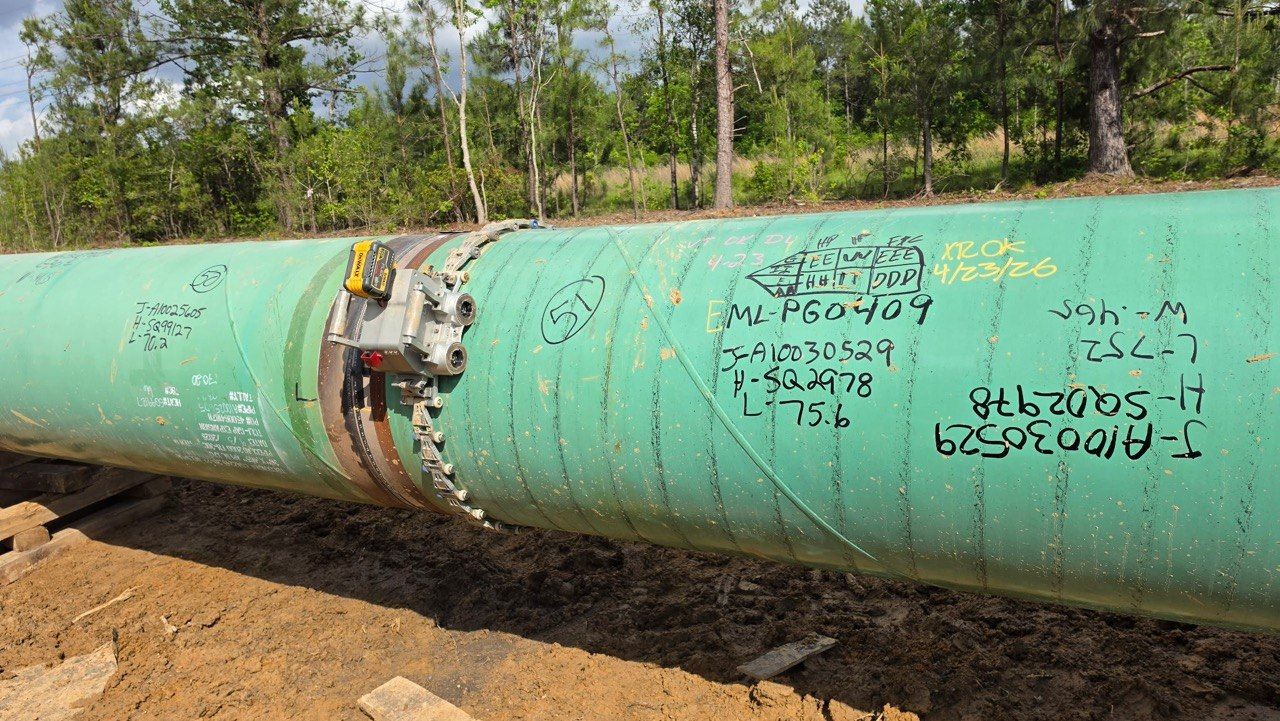 Pipeline girth weld with a band clamp in place and weld identification markings on the pipe