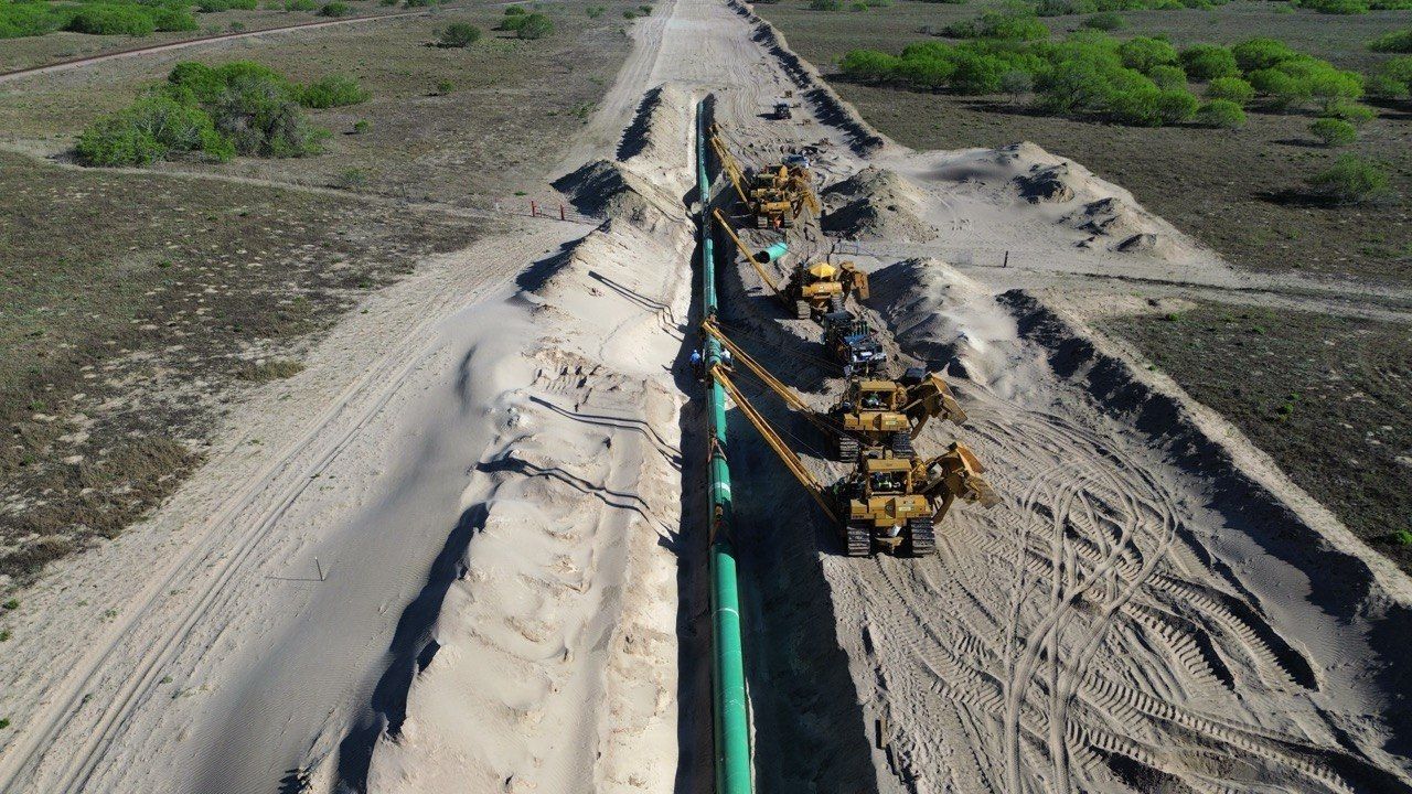 Drone view of a pipeline being lowered into the ditch by sidebooms