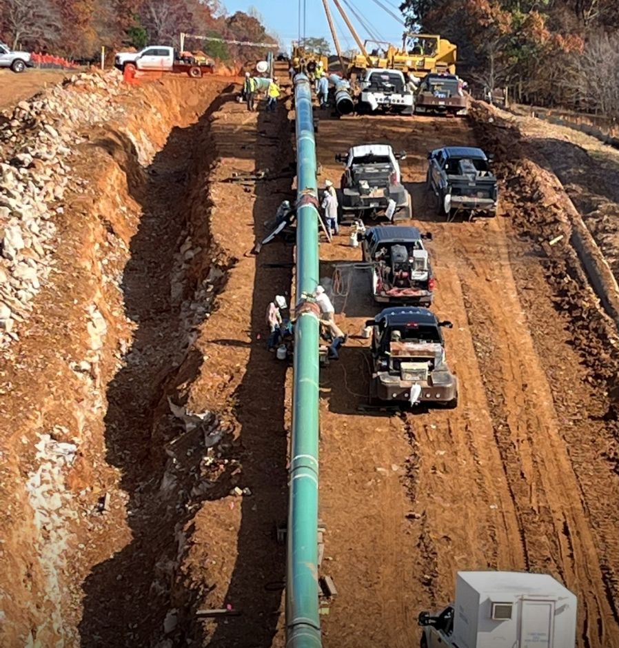 Coated pipeline string on a construction right-of-way with excavated trench alongside